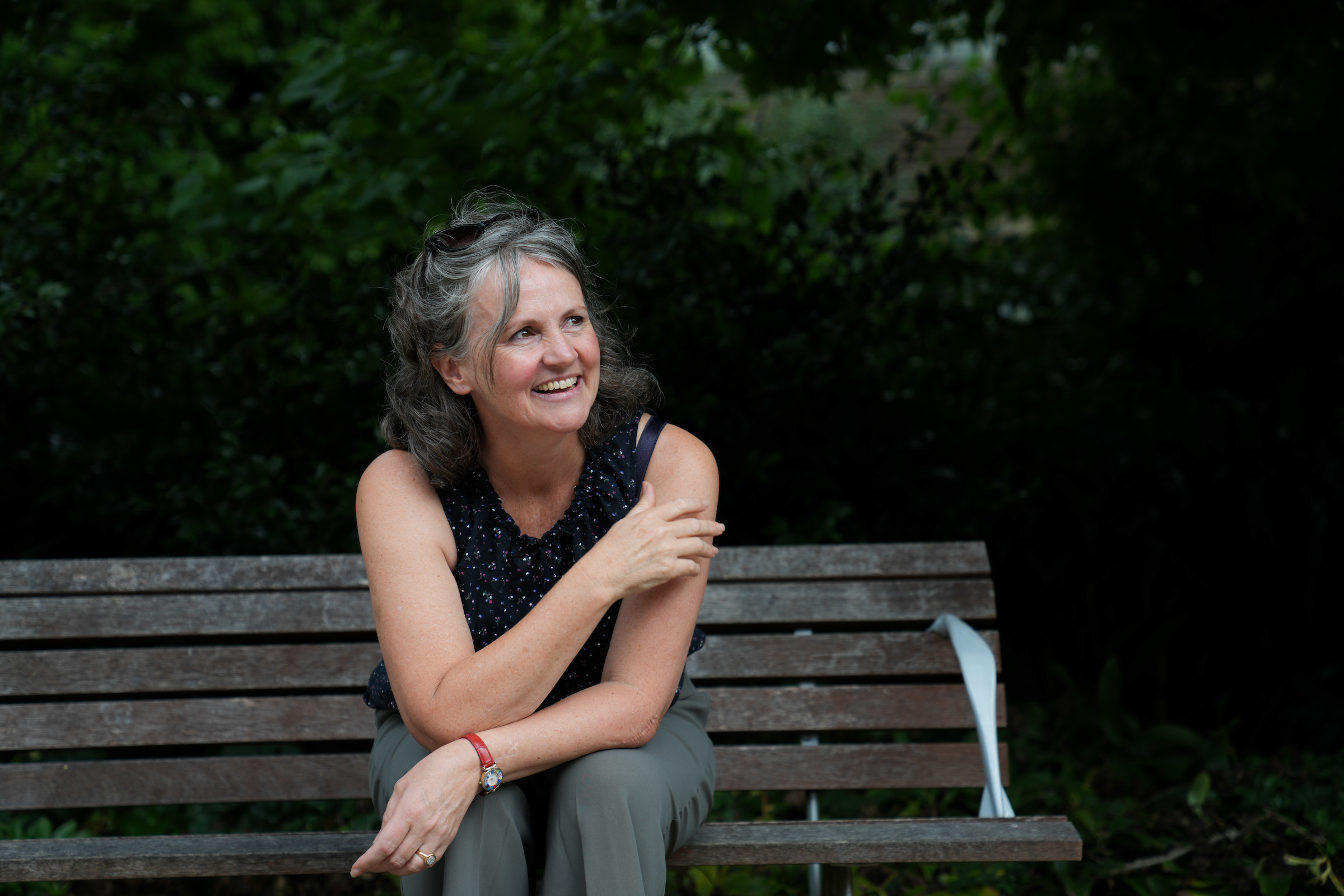 Sarah Mann sits outside on a park bench.