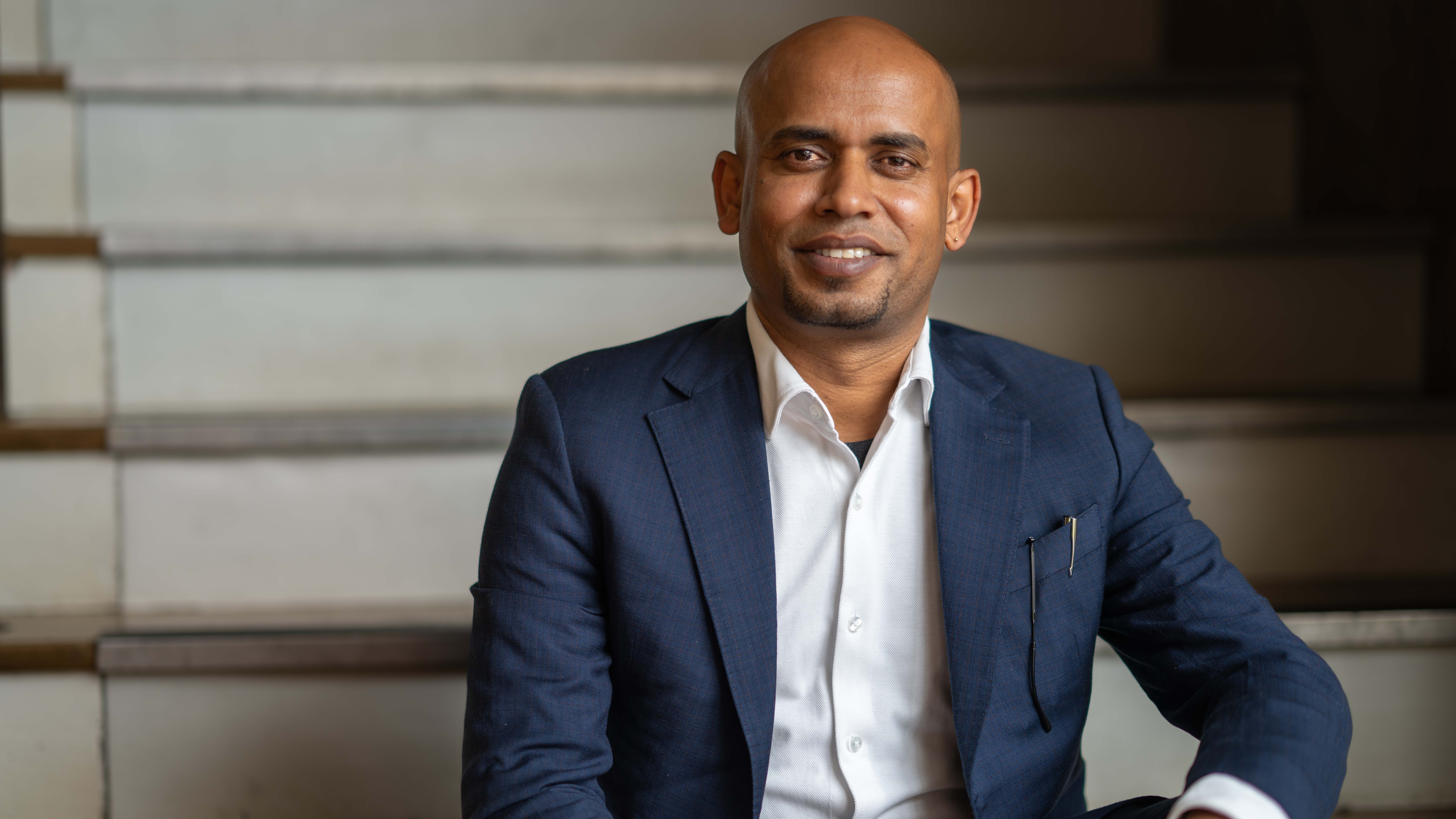 Dr Uday Yadav sits on some stairs for a portrait photo.