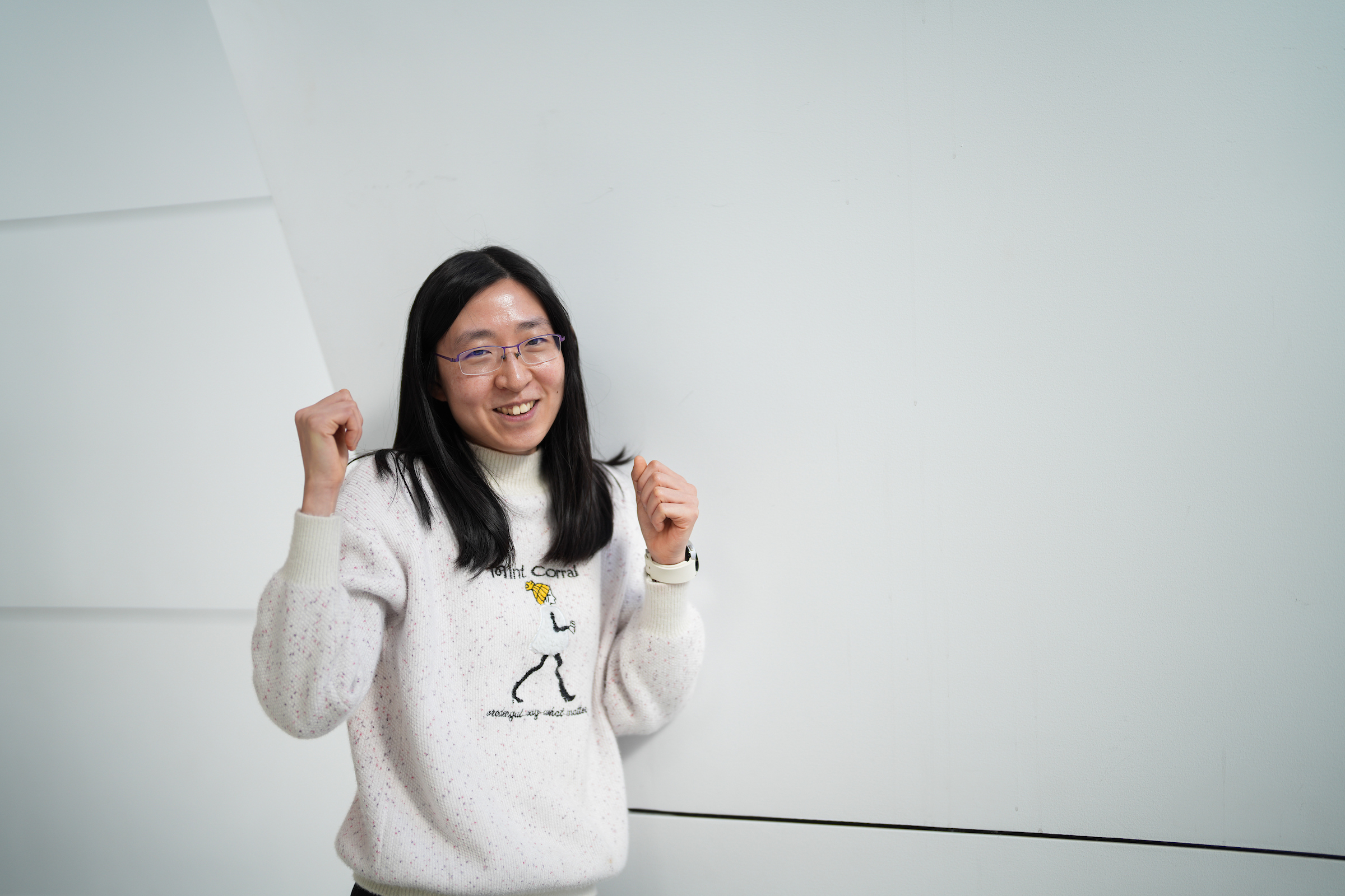 Sasanan Trakansuebkul with her arms in the air celebrating her 3 minute thesis win.
