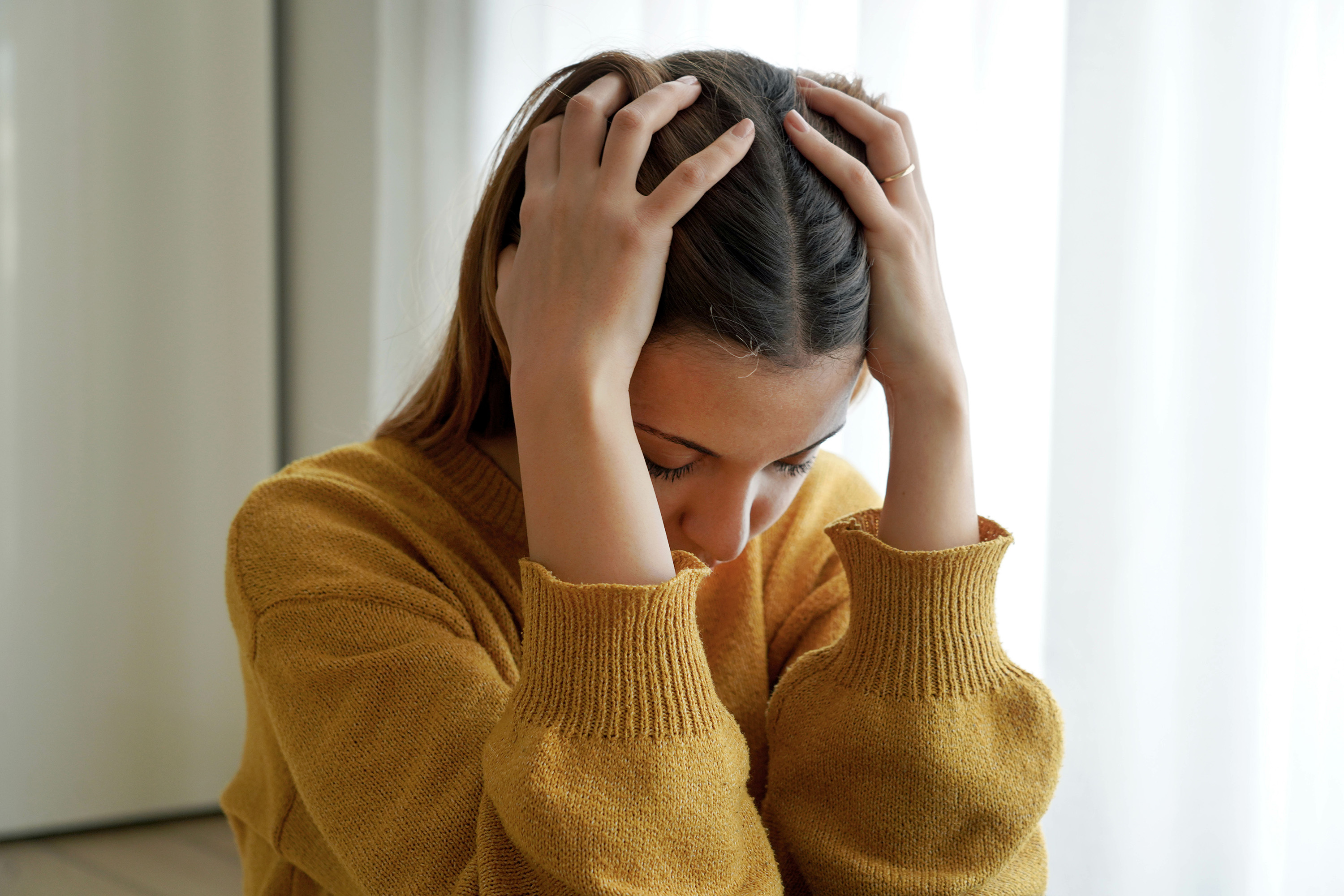 woman holding head in hands looking upset