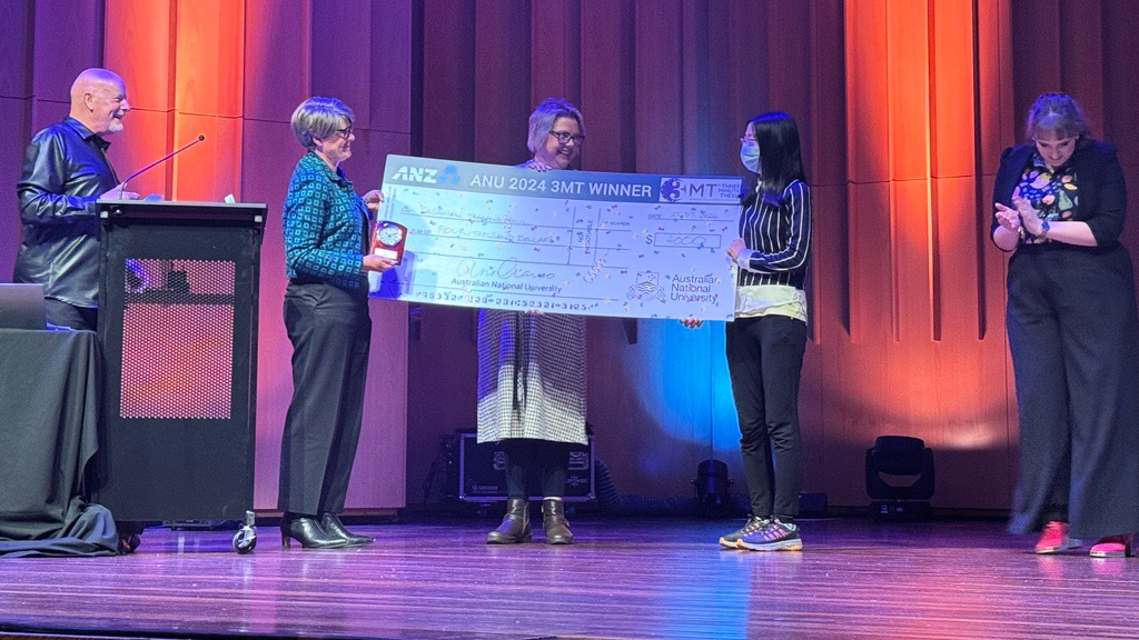 Sasanan Trakansuebkul on stage with the ANU 3-minute thesis winner's cheque.