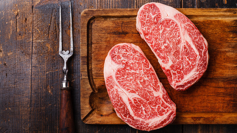 Two pieces of red meat on a wooden board