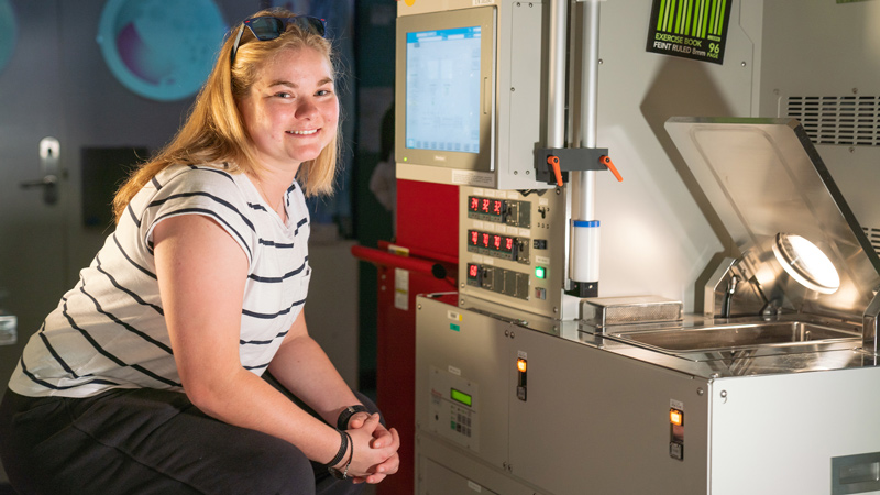 Ellen Brown, a young woman with type 1 diabetes, sitting in a lab of the ANU and smiling into the camera.