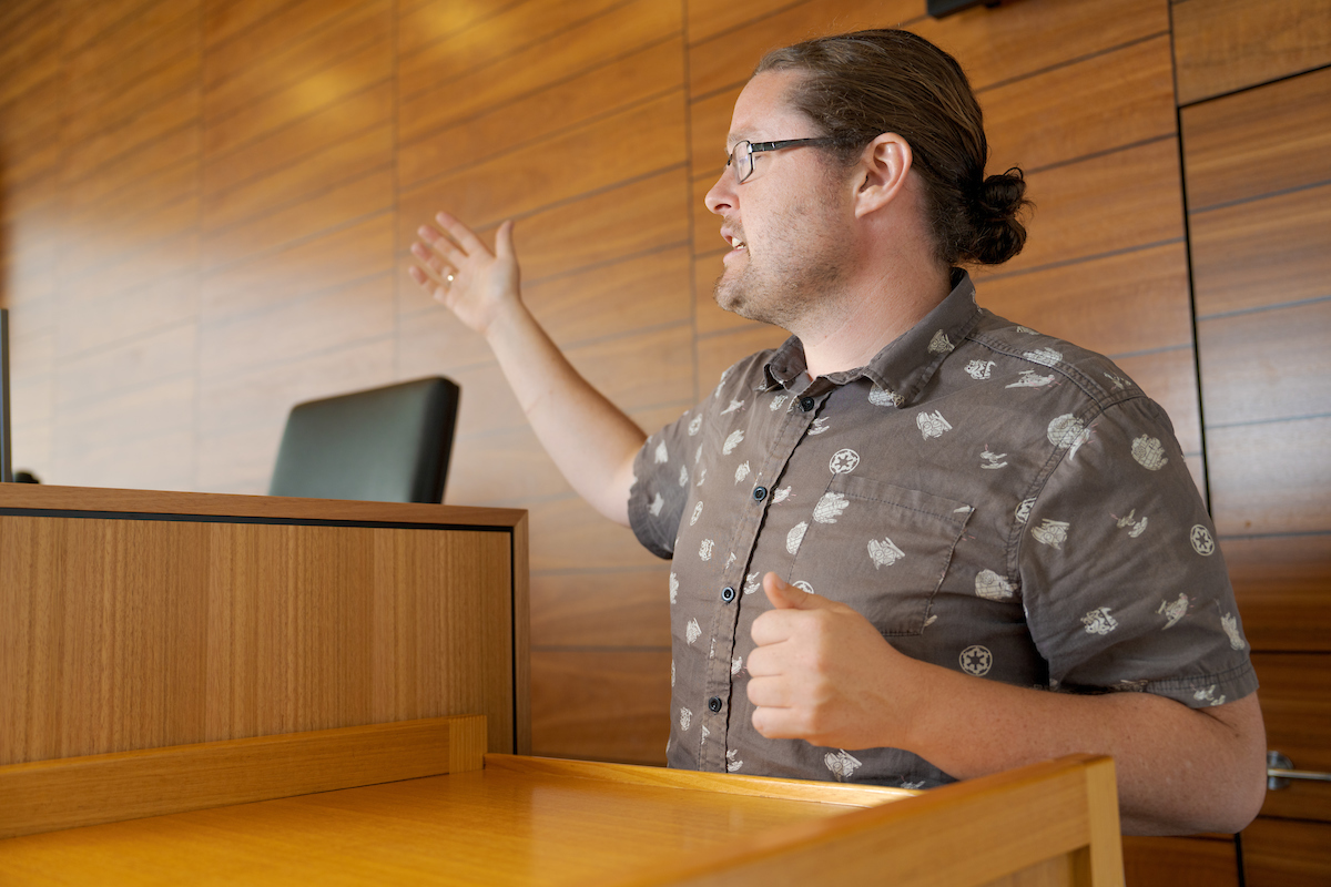 Dr Brad Tucker at the ANU College of Law Moot Court A man in a brown shirt standing in a court dock