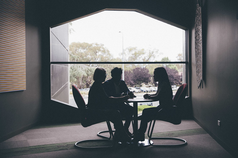 Three people sitting at a table by a window