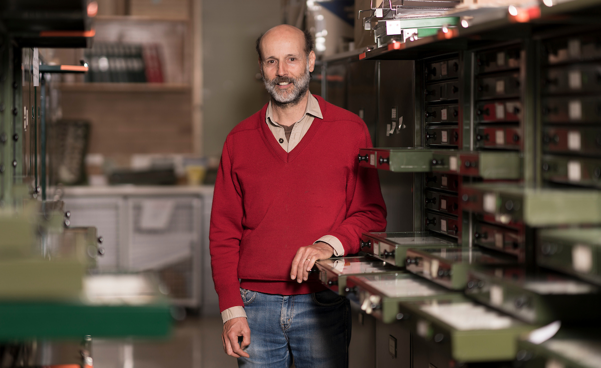 Headshot of a man next to insect collection