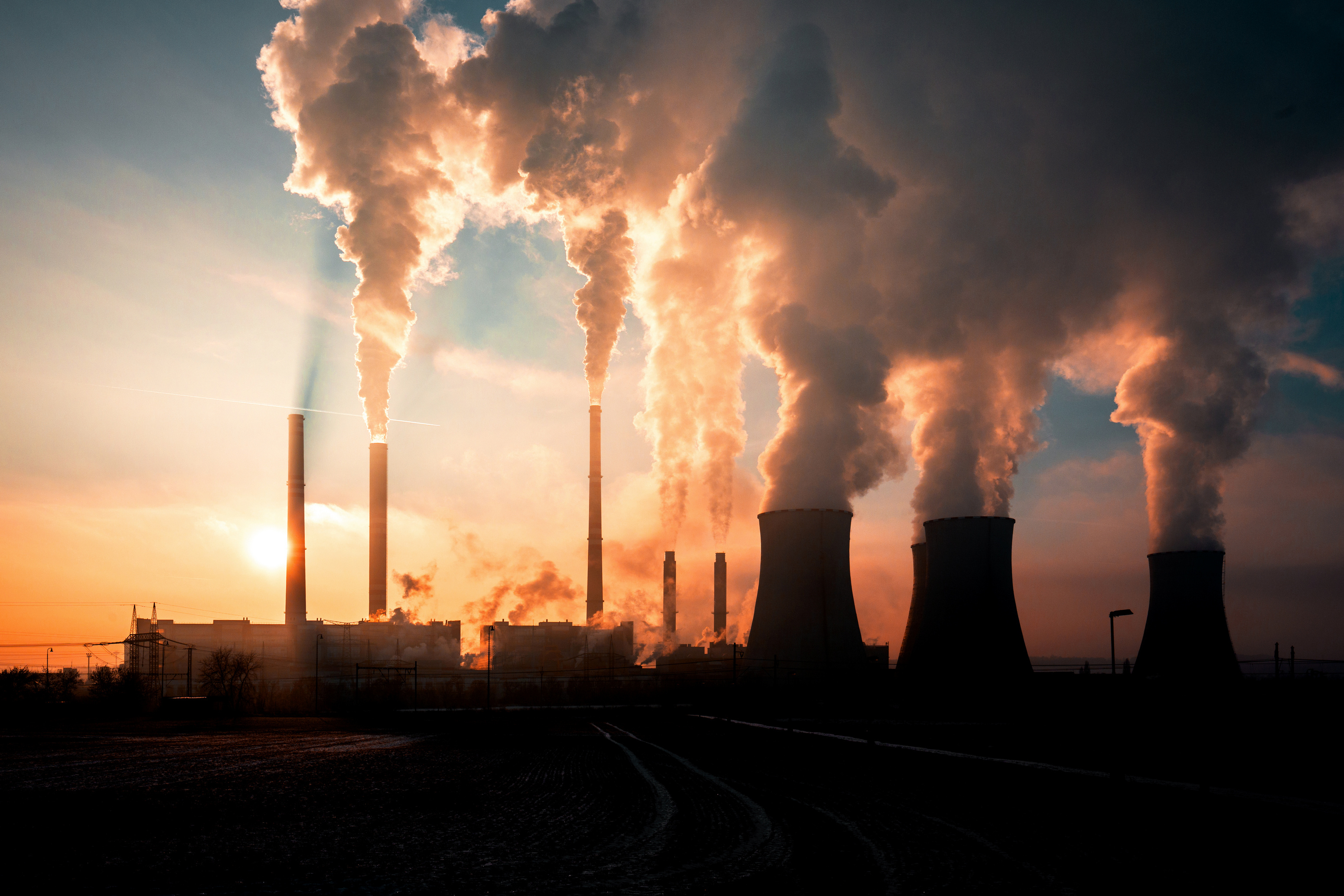 Photo: Adobe Stock A powerplant with plumes of pollutants at sunset