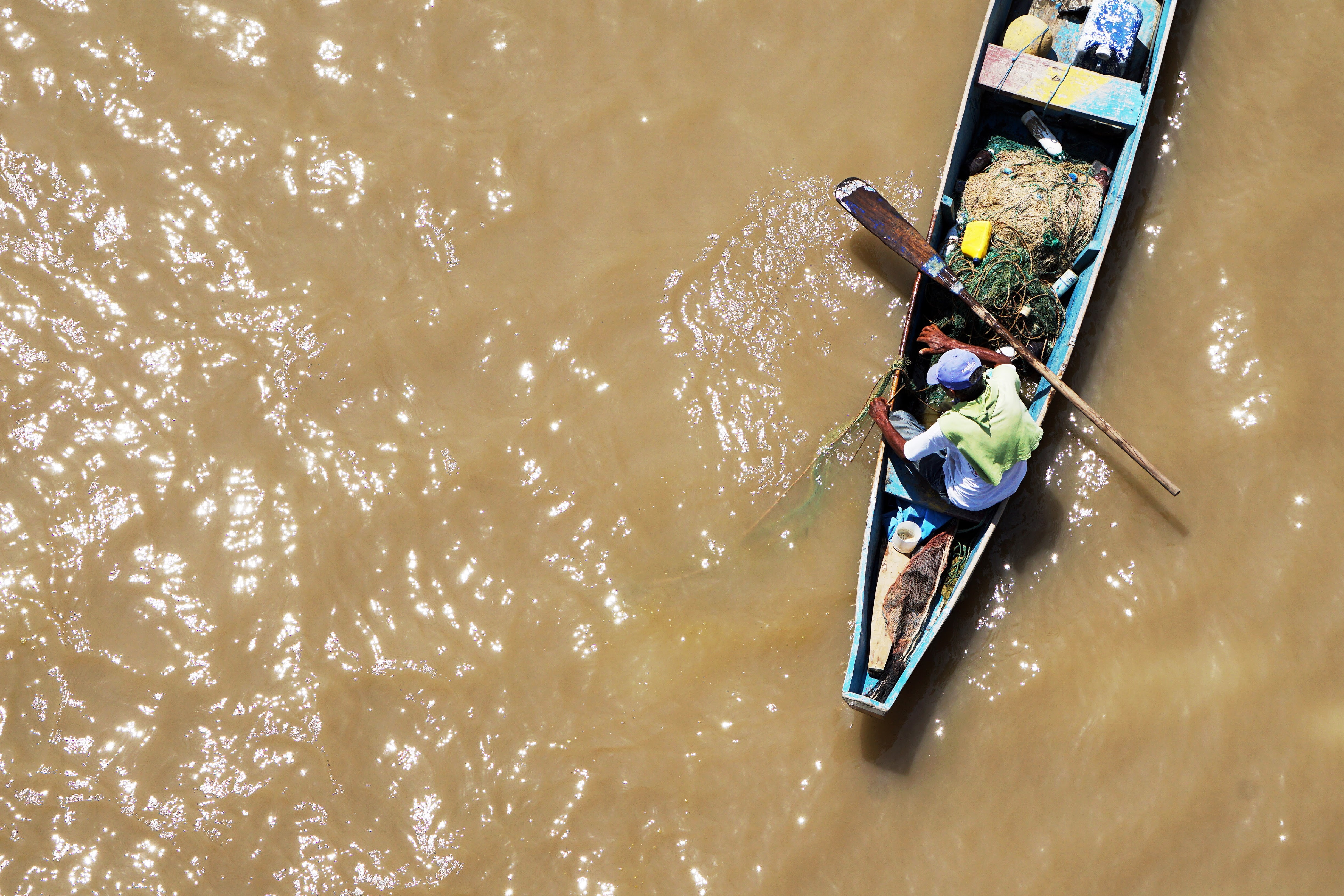 Man in a fishing boat on brown water