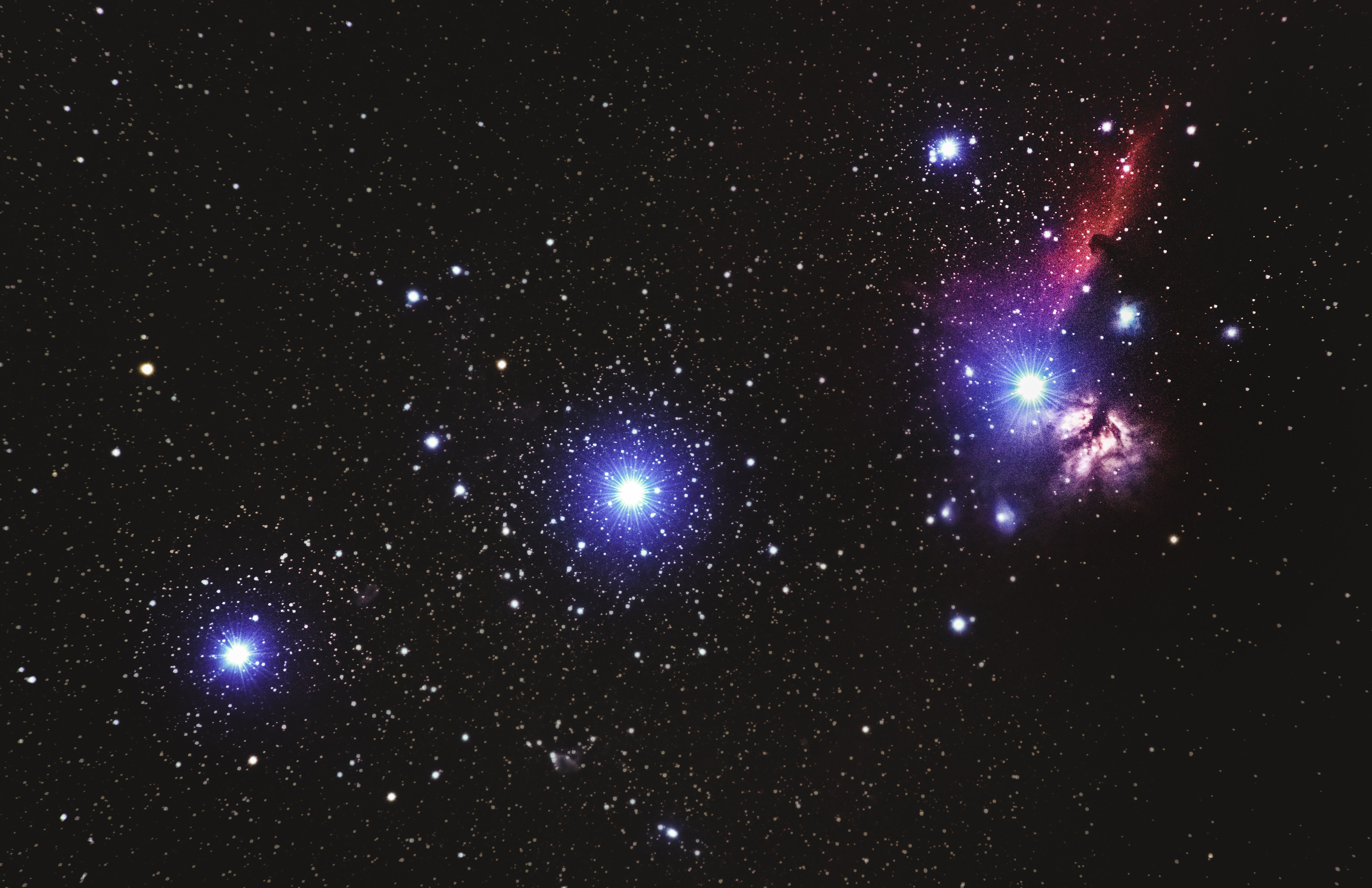 A vibrant image of a star cluster and a colorful nebula set against a dark starry sky.