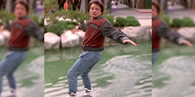 A person appears to be balancing while moving on a transparent, reflective surface in a public space, implying an action of gliding or skating.