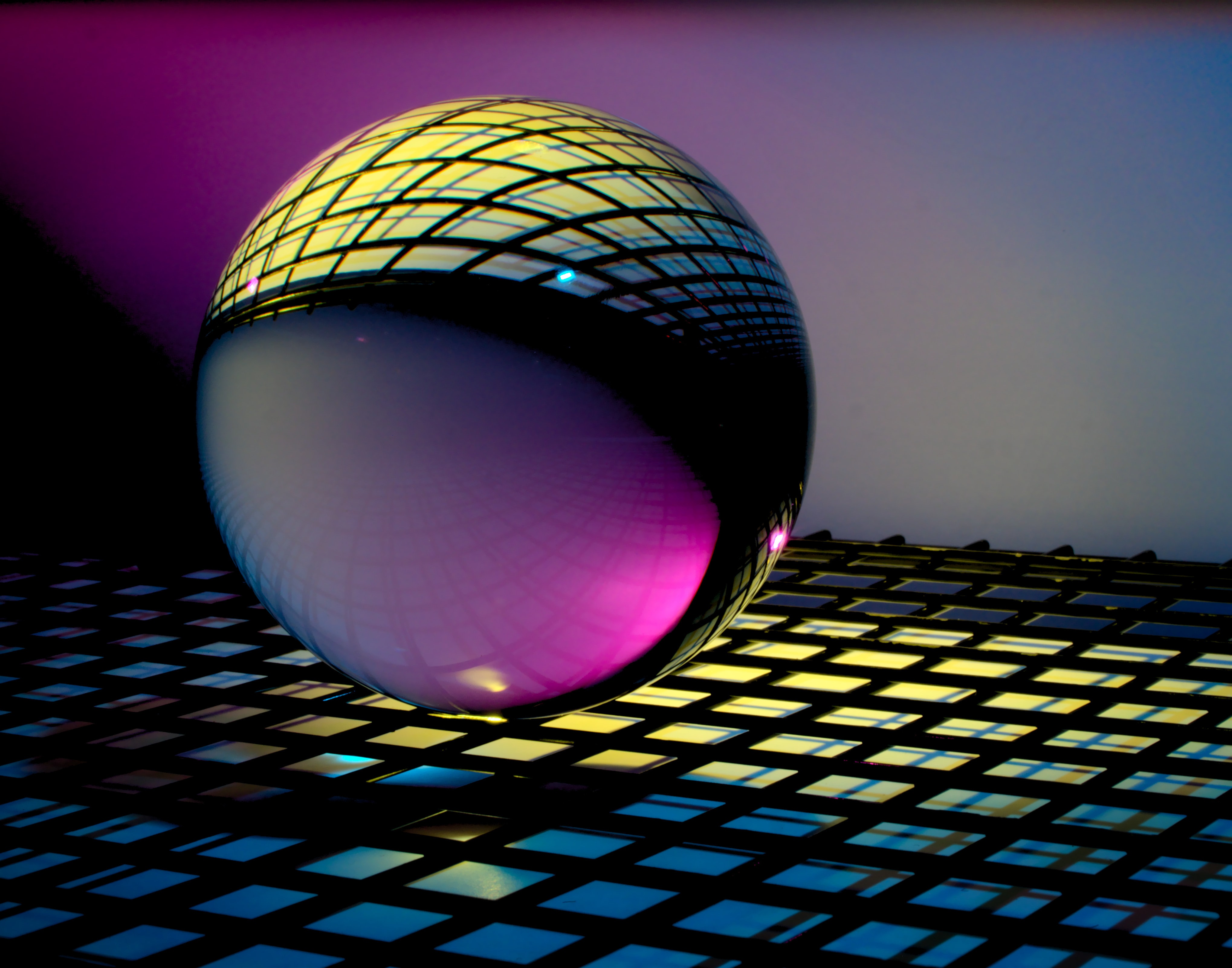 A reflective sphere casts colorful lights on a checkered surface under a gradient of purple to pink lighting.