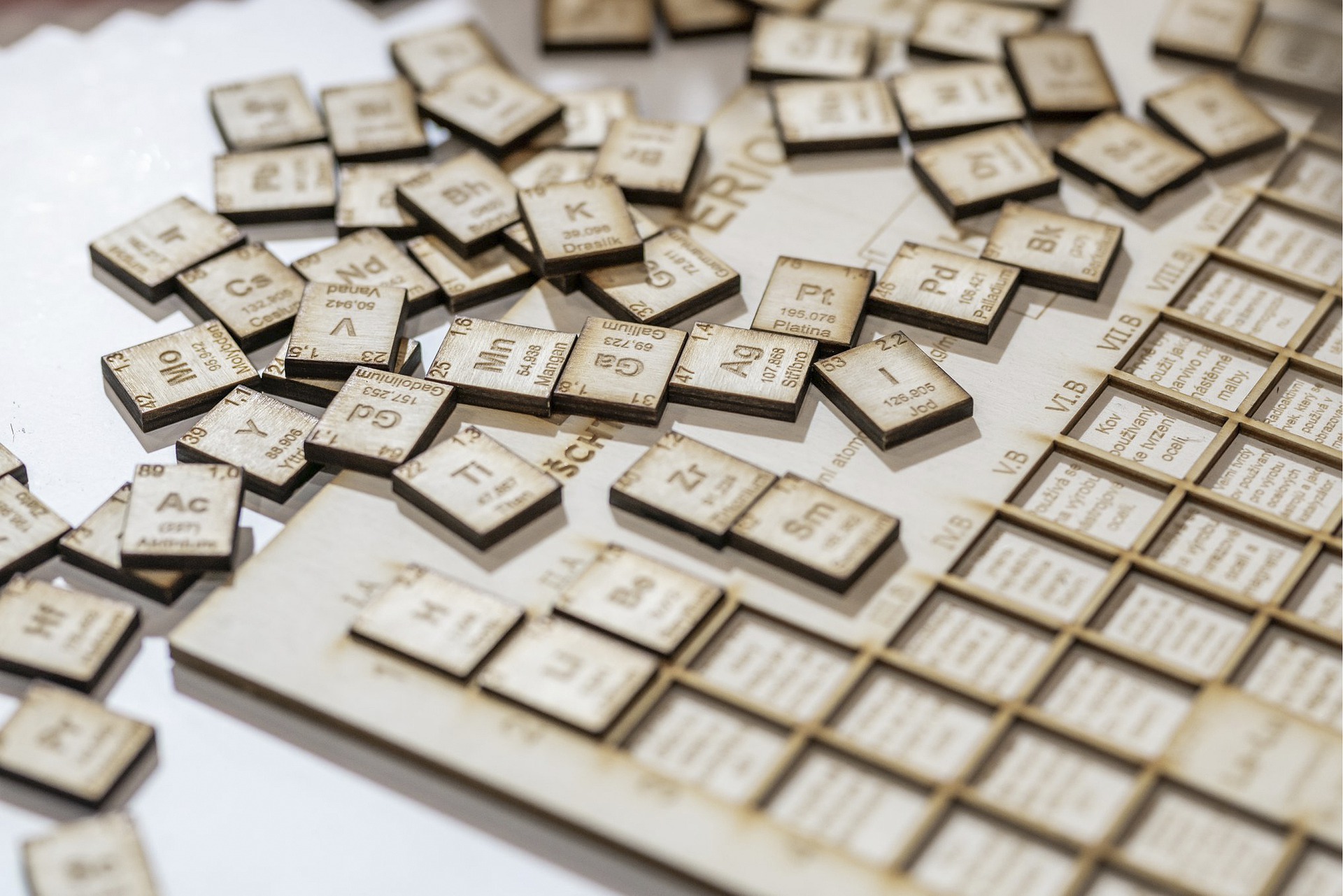 A collection of wooden periodic table element tiles scattered on a surface.