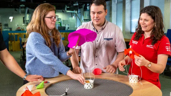 Three people testing a small parachute as part of a science experience