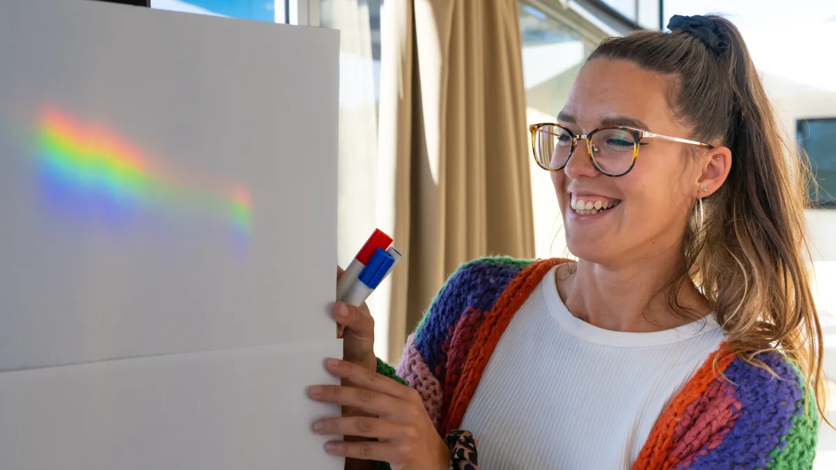 Women next to a rainbow on white cardboard