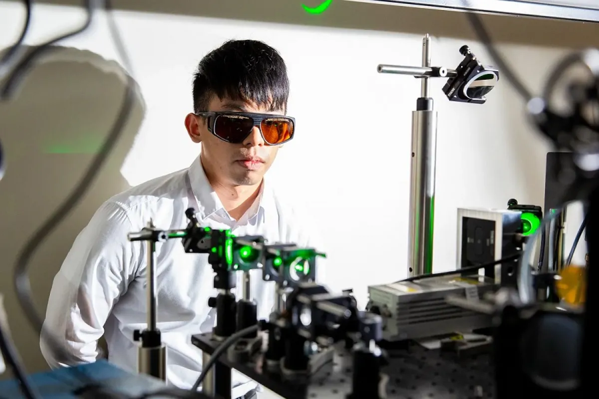 Man with safety goggles and a lab coat with laser equipment