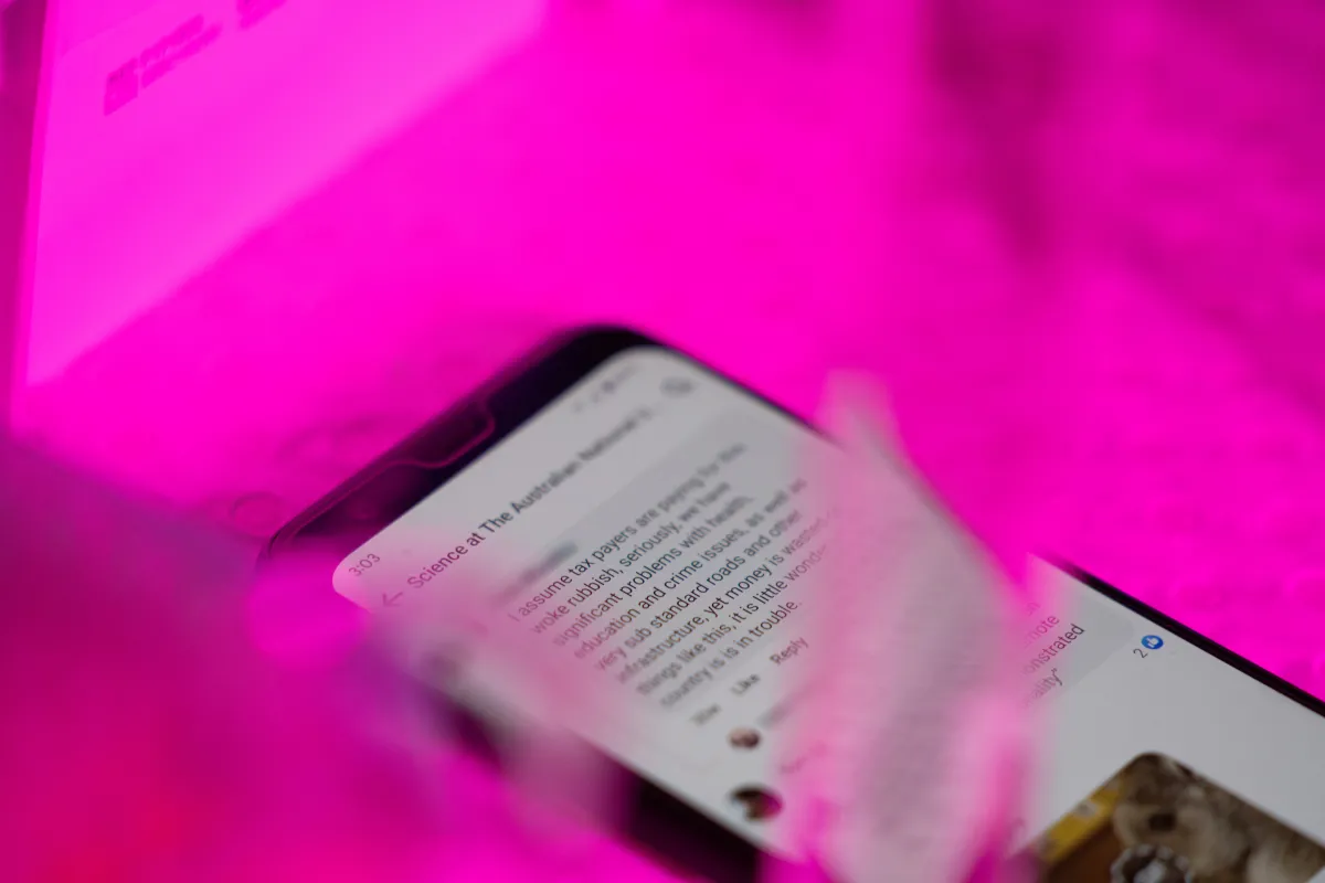 A phone lies on a lab desk with a comment complaining about wasting taxpayer funds