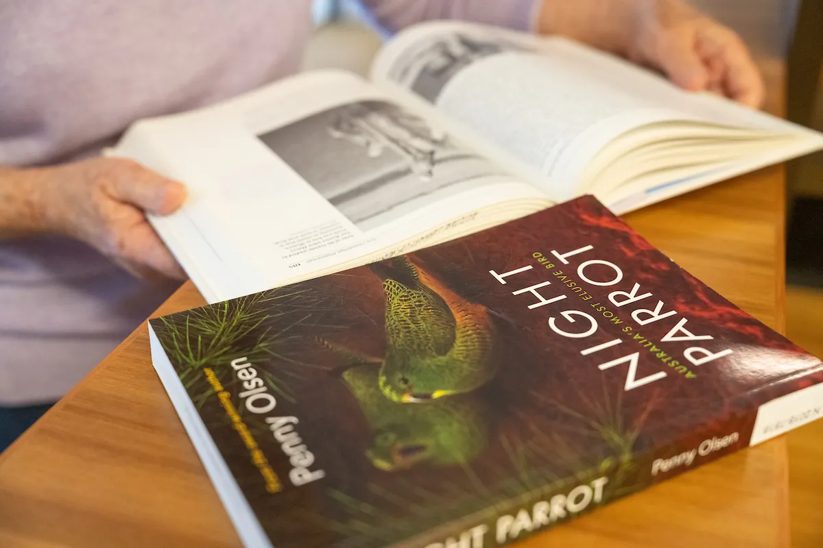 A book called Night Parrot and a woman's hands reading