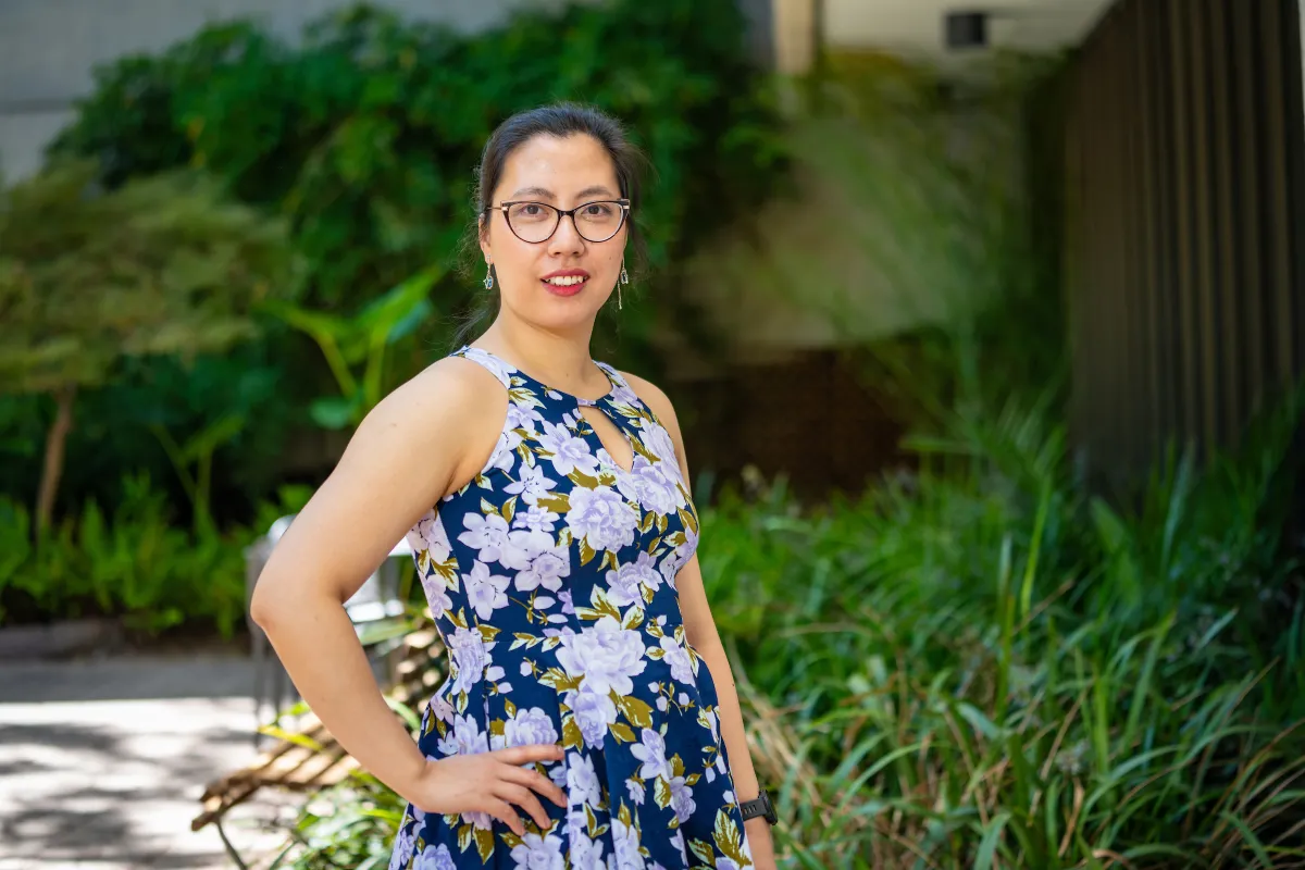 A woman in a purple floral dress with her hand on her hip