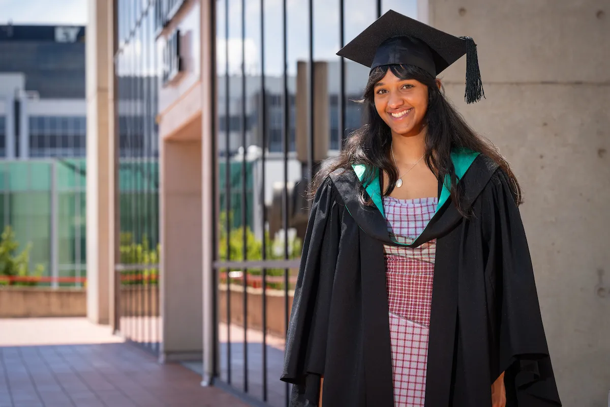 Woman in graduation gown and hat smiling