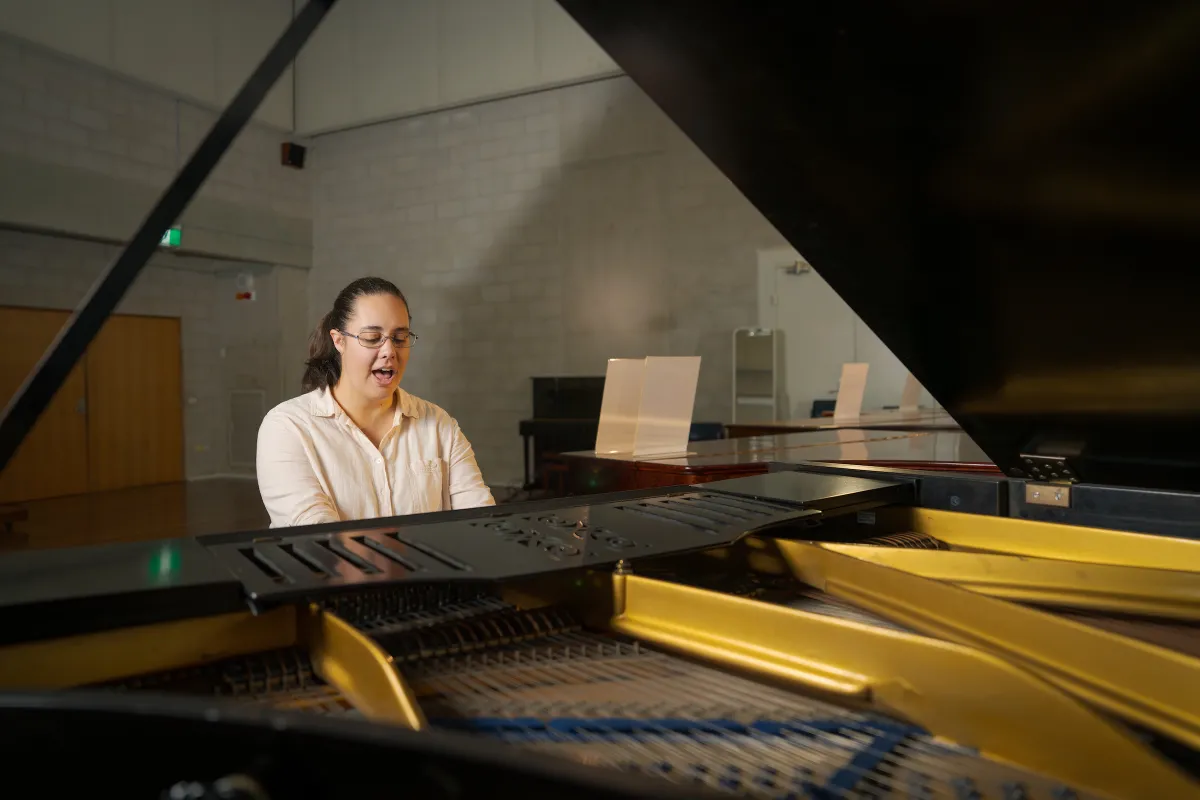 A woman at a piano, singing
