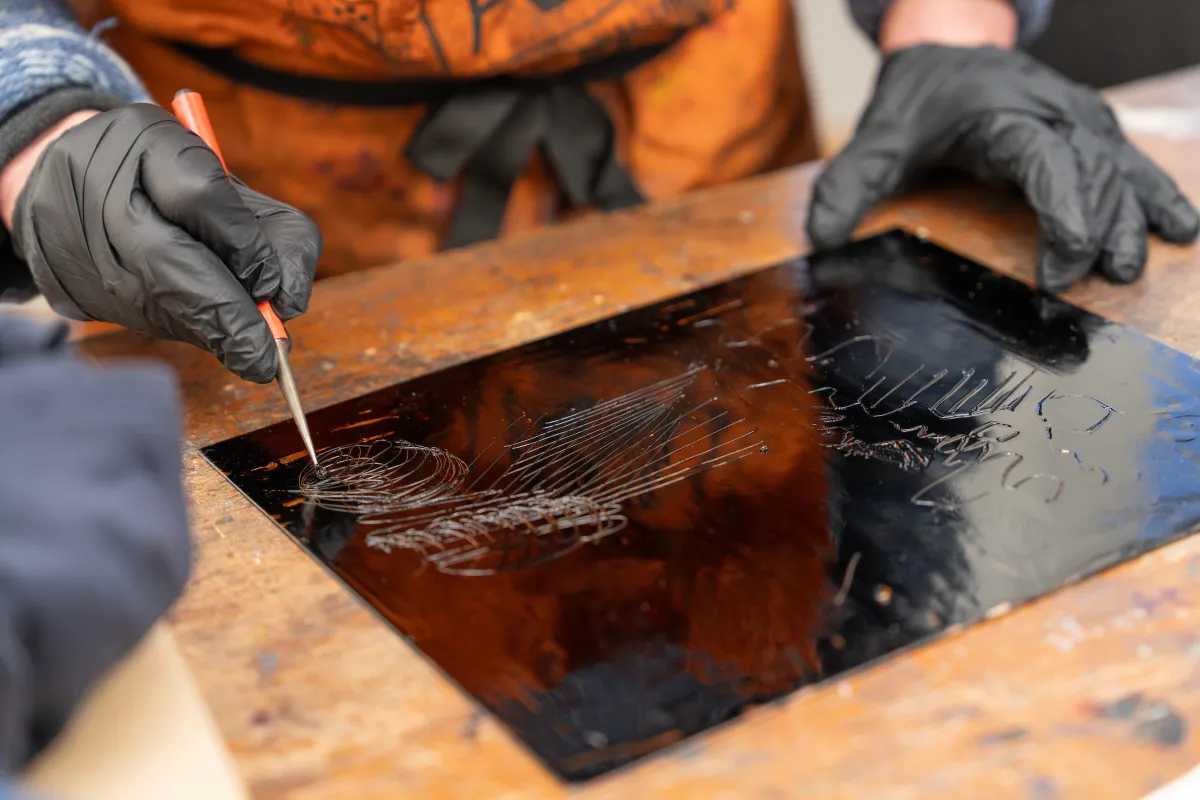 Close up image of etching plate that Susanne Ilschner is engraving by hand.