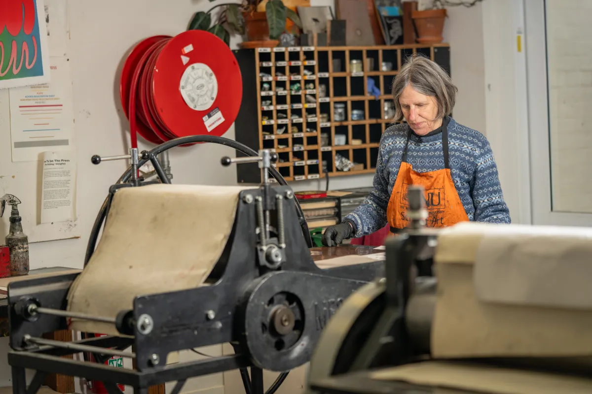 Susanne Ilschner is in an art studio using a printing press