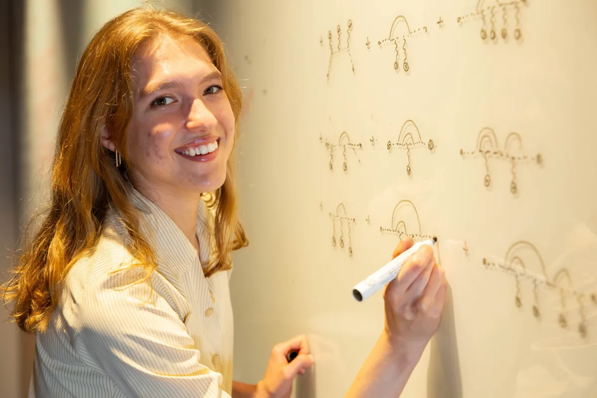 A woman writing equations on a whiteboard