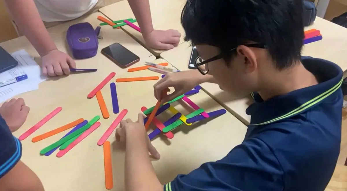 A student building a bridge with pop sticks