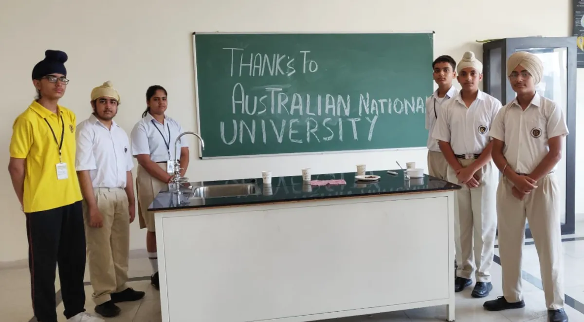 A group of students standing in front of a green board