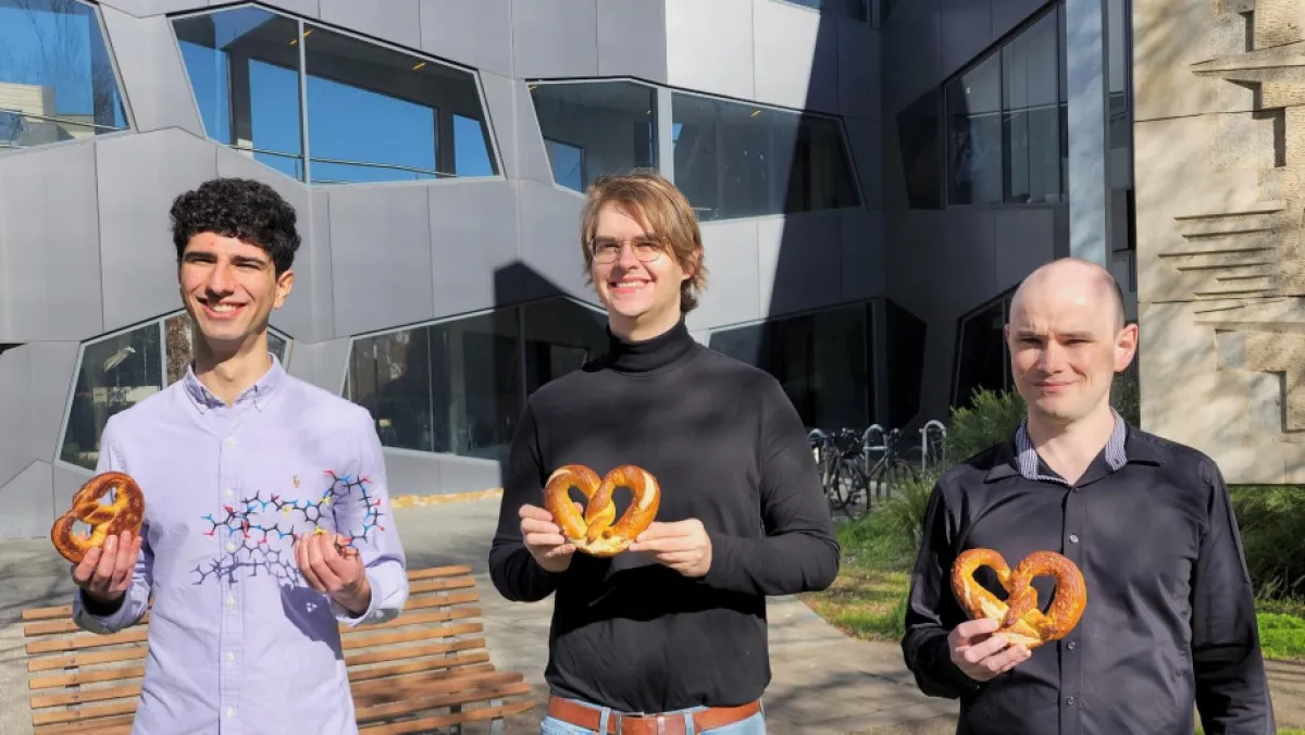 3 researchers holding pretzels and a 3D molecular model.