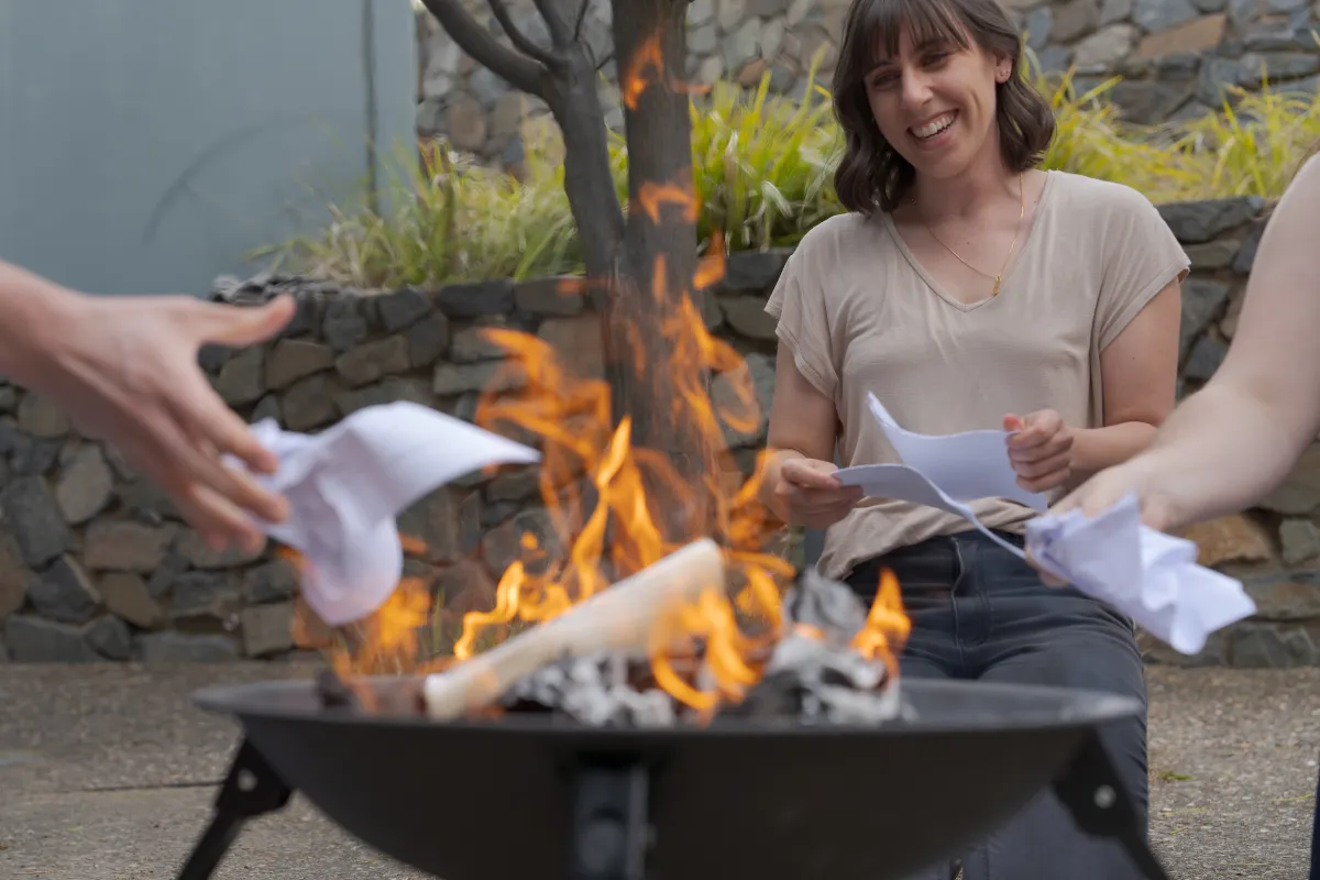 Hands throwing papers into a firepit