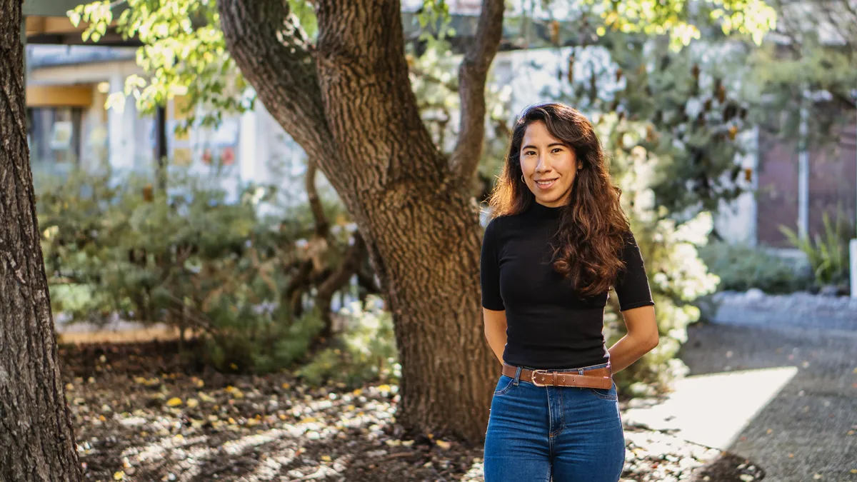 Dr Ana Casas Ramos outside in front of a tree and small garden.