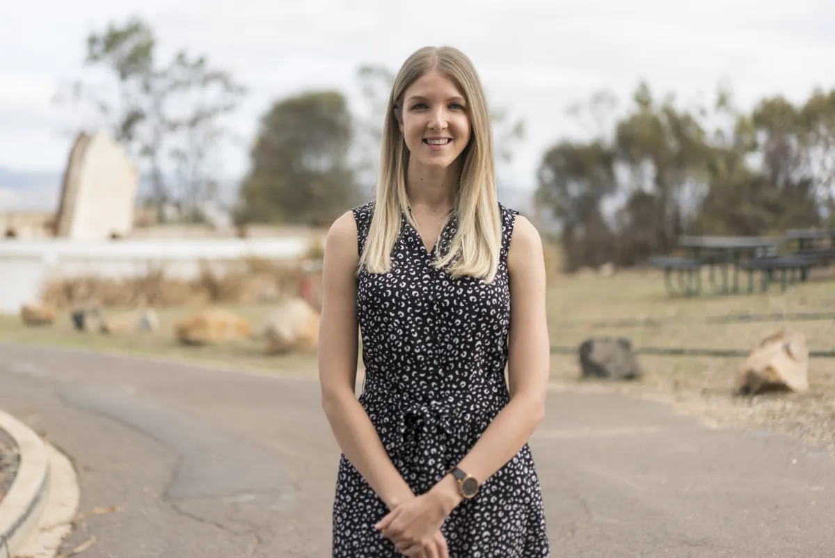 Shanae King is standing outside with remains of telescopes in the background.