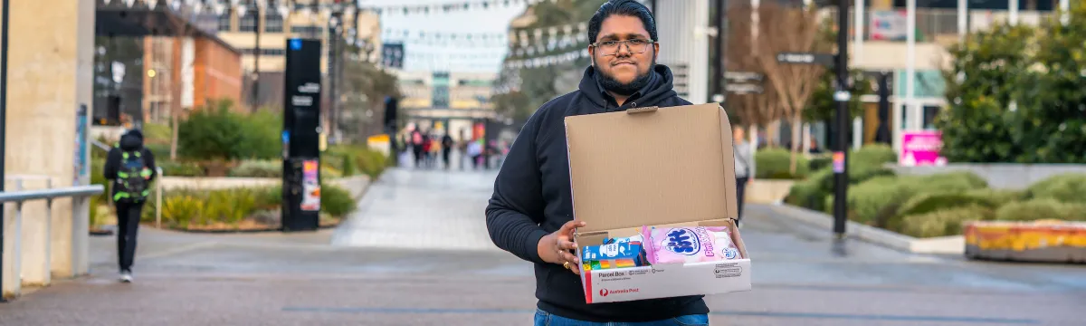 Sreenath Didugu standing on a street with a box full of science activities