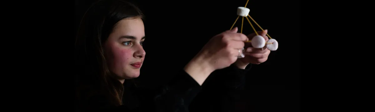 Young woman looking at spaghetti and marshmallow structure