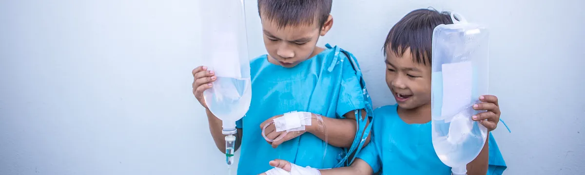 Two boys holding medical fluid bags
