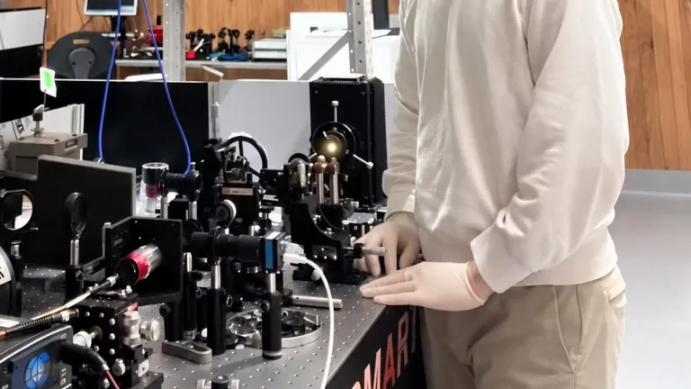 Physicist wearing eye protection standing next to a laser