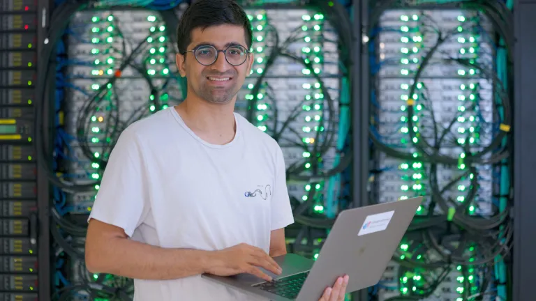 A man standing in front of computer servers with a laptop