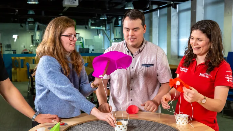 Three people testing a small parachute as part of a science experience