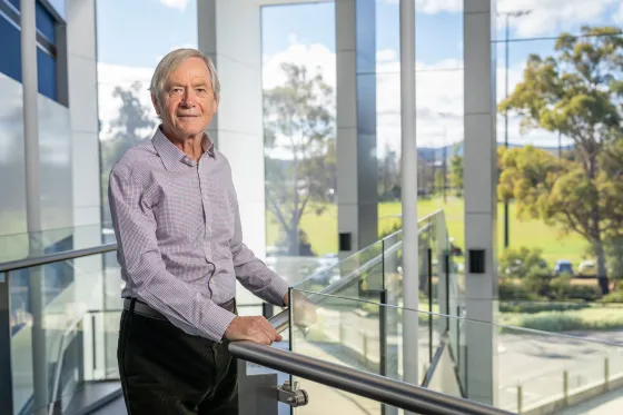 Professor Trevor Lamb inside a light filled foyer overlooking a green campus