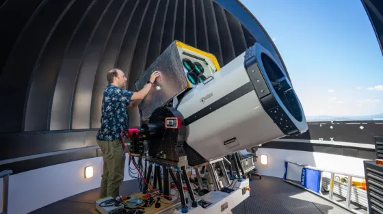 Researcher Francis Bennet is operating a large telescope inside a telescope dome that is open to the sky.