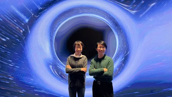 Dr Ling Sun and and Mr Neil Lu are in front of a large illustration of a black hole.