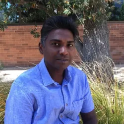 A man in a blue shirt in front of some grasses