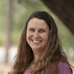 A smiling woman in a purple shirt