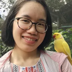 A girl with glasses with a yellow bird on her shoulder