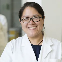 A woman wearing a lab coat smiling