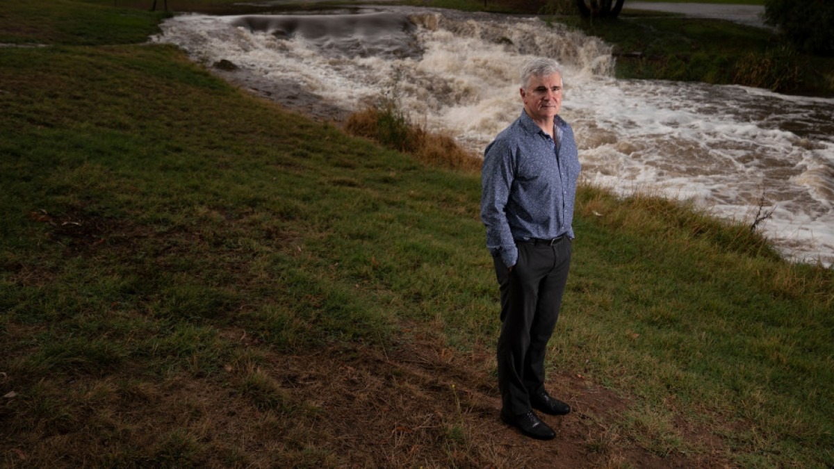Prof Mark Howden stands outside next to a running stream.