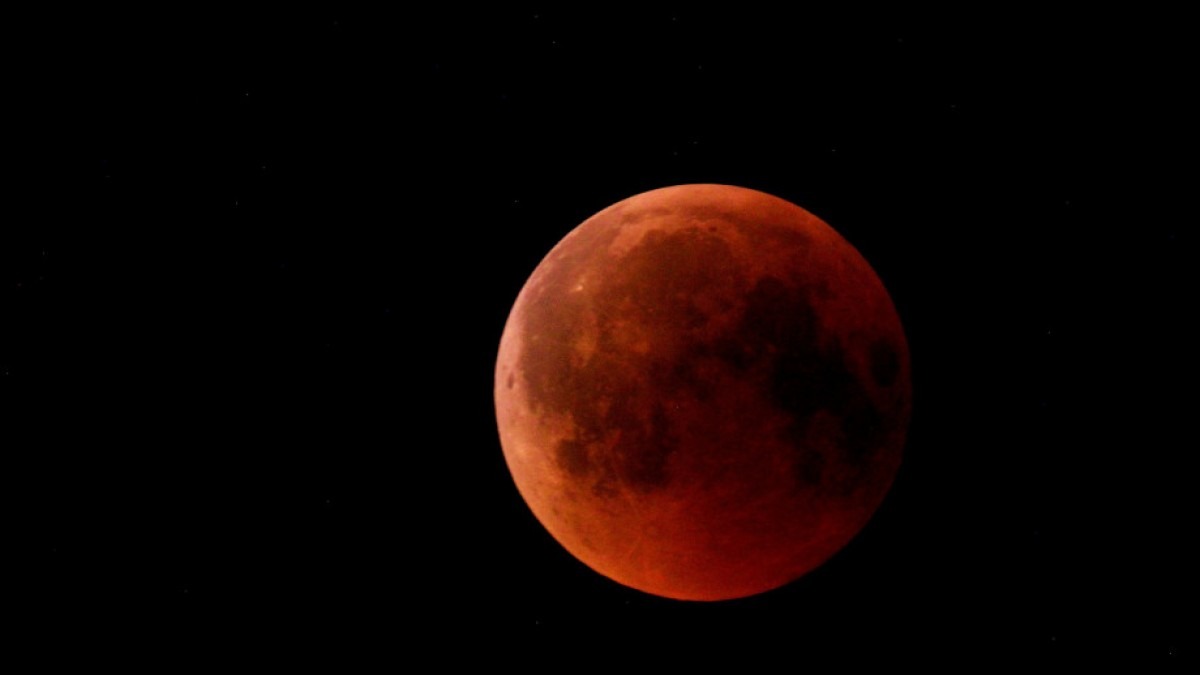 Blood red coloured full moon in night sky