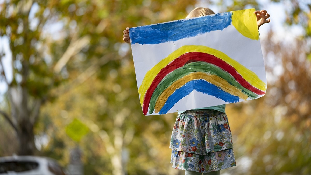 Child holding rainbow painting