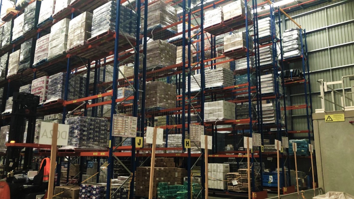 A Foodbank warehouse full of stacked food and crates.